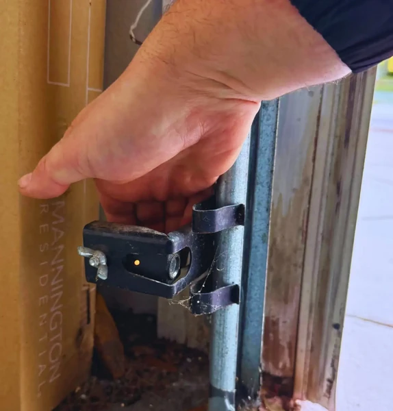 A technician's hand on a door hinge — attention to the small things that hold the whole