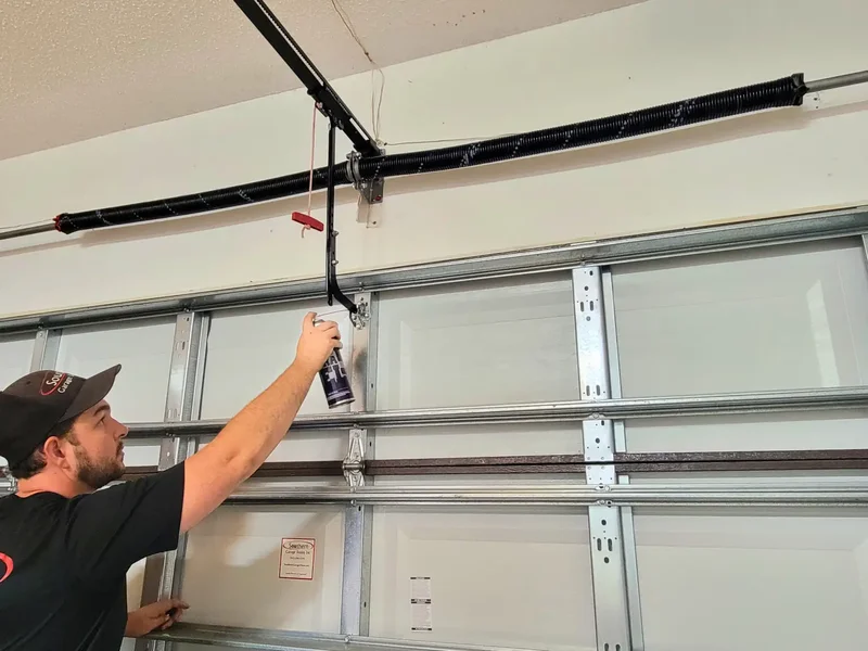 Technician applying lubricant to garage door rollers